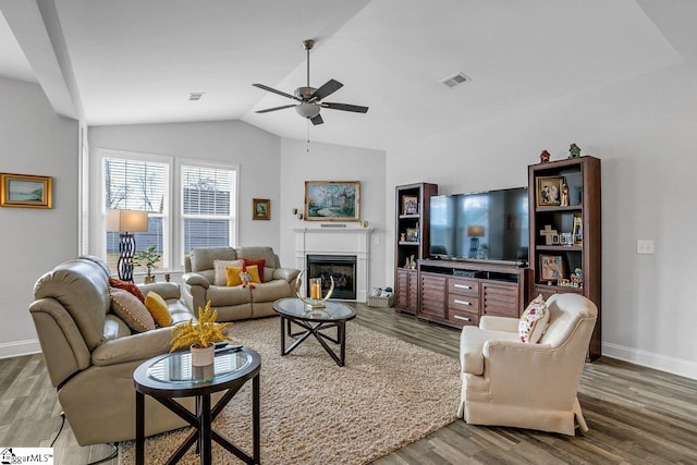 living area featuring visible vents, a ceiling fan, a glass covered fireplace, lofted ceiling, and wood finished floors