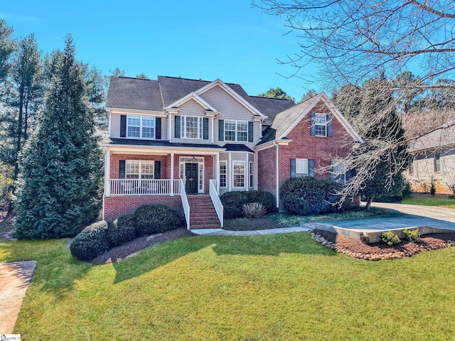 traditional-style home featuring covered porch, a front yard, and brick siding