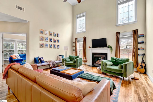 621 Shefwood Dr, Easley, SC 29642 - living room featuring ceiling fan, a fireplace with flush hearth, a towering ceiling, visible vents, and light wood finished floors