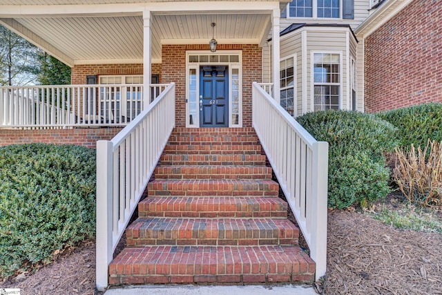 property entrance with covered porch and brick siding