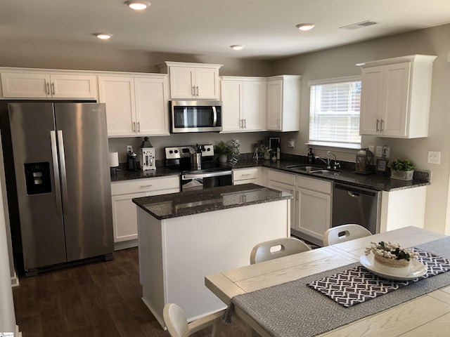 kitchen with appliances with stainless steel finishes, white cabinets, visible vents, and a sink