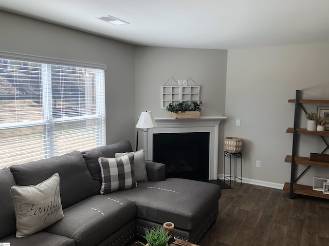 living room featuring dark wood-style floors, visible vents, a fireplace, and baseboards