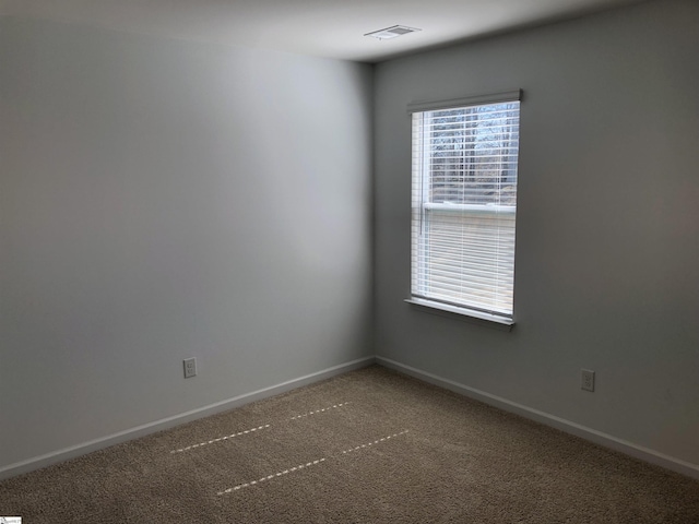 spare room featuring carpet, visible vents, and baseboards