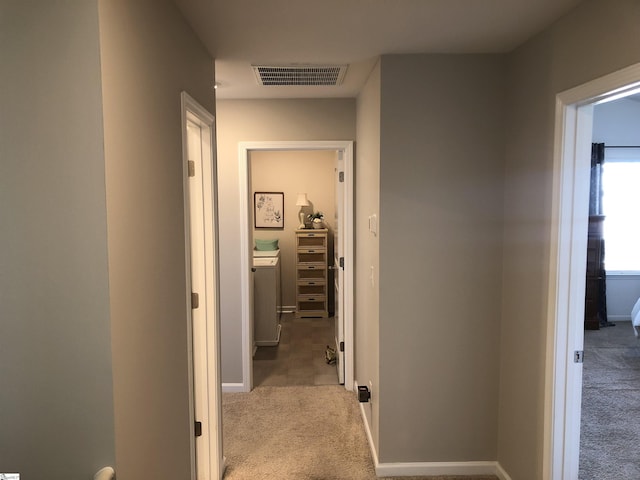 hall featuring baseboards, visible vents, and carpet flooring