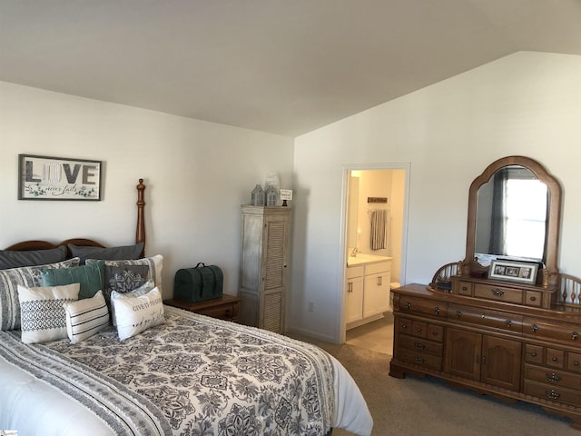 bedroom with lofted ceiling, carpet floors, and ensuite bath