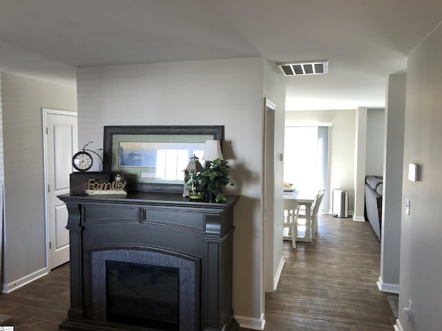 corridor with dark wood-style floors, baseboards, and visible vents