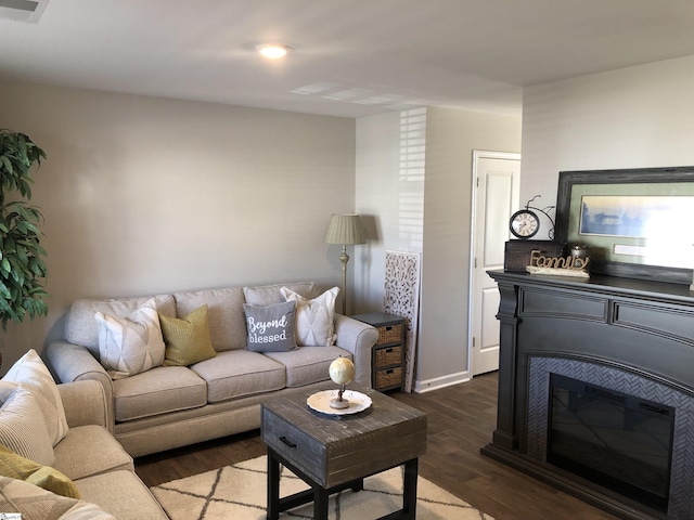 living room with dark wood-style floors, a glass covered fireplace, and visible vents