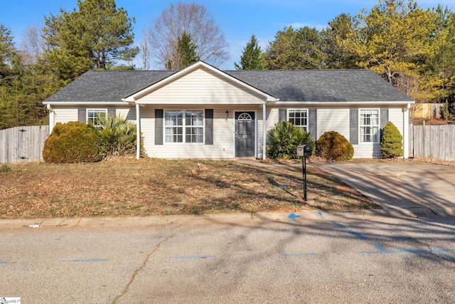 single story home featuring a shingled roof and fence