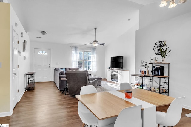 dining room featuring baseboards, visible vents, a ceiling fan, lofted ceiling, and wood finished floors