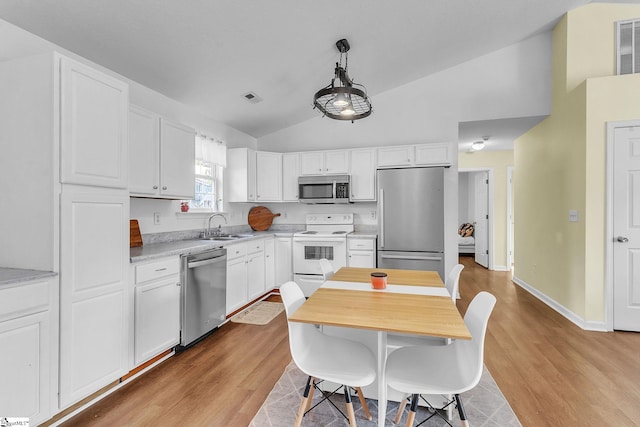 kitchen featuring white cabinets, vaulted ceiling, stainless steel appliances, and light countertops