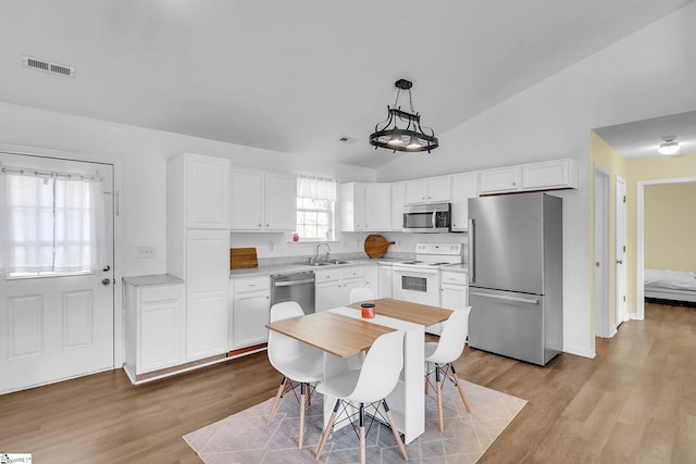 kitchen with stainless steel appliances, a sink, visible vents, vaulted ceiling, and light countertops