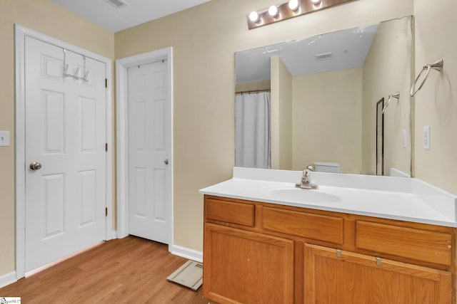 full bath featuring visible vents, wood finished floors, vanity, and baseboards