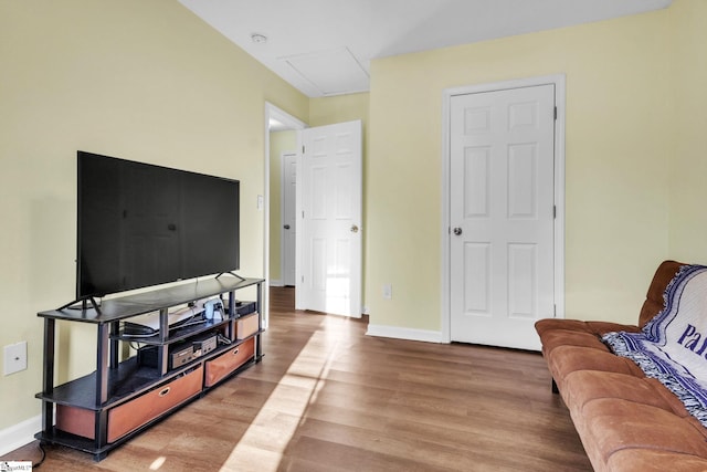 living room featuring wood finished floors, attic access, and baseboards