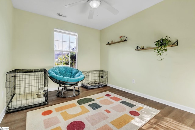 sitting room with a ceiling fan, baseboards, visible vents, and wood finished floors