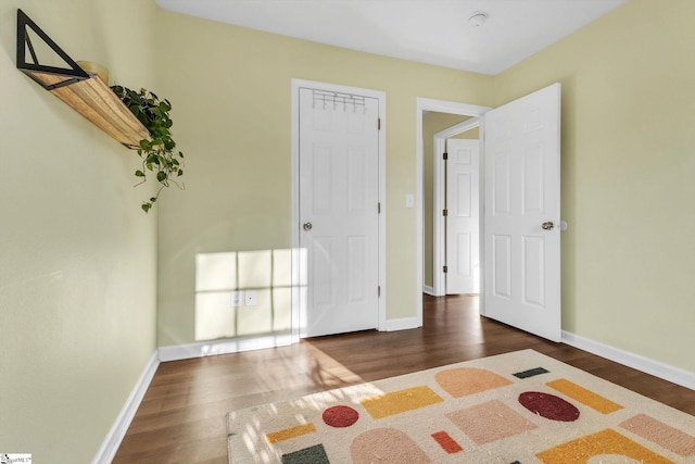 unfurnished bedroom with dark wood-style flooring and baseboards