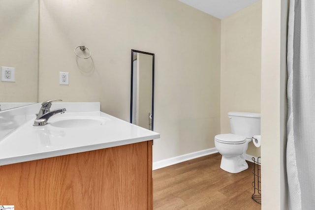 bathroom featuring baseboards, vanity, toilet, and wood finished floors