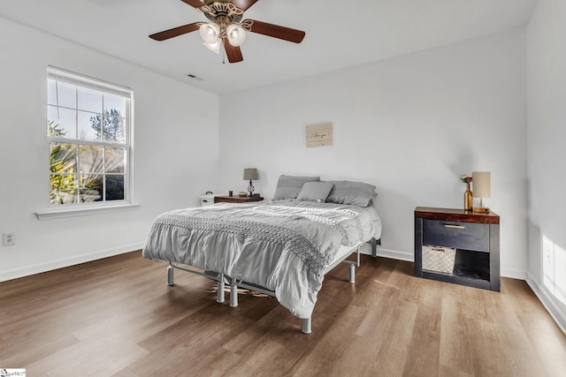 bedroom with ceiling fan, baseboards, and wood finished floors