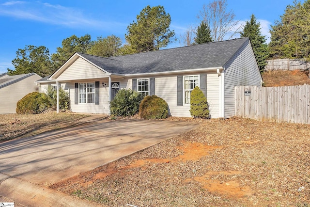 ranch-style home with a shingled roof and fence