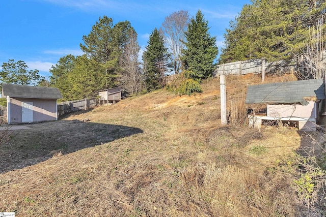 view of yard with an outbuilding, fence, and a shed