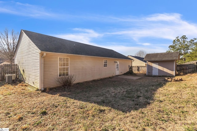 view of side of home featuring an outbuilding, a fenced backyard, central air condition unit, a lawn, and a storage unit