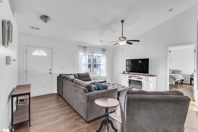 living room featuring ceiling fan, visible vents, vaulted ceiling, and wood finished floors