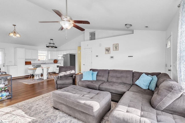 living area with dark wood-type flooring, ceiling fan, and high vaulted ceiling