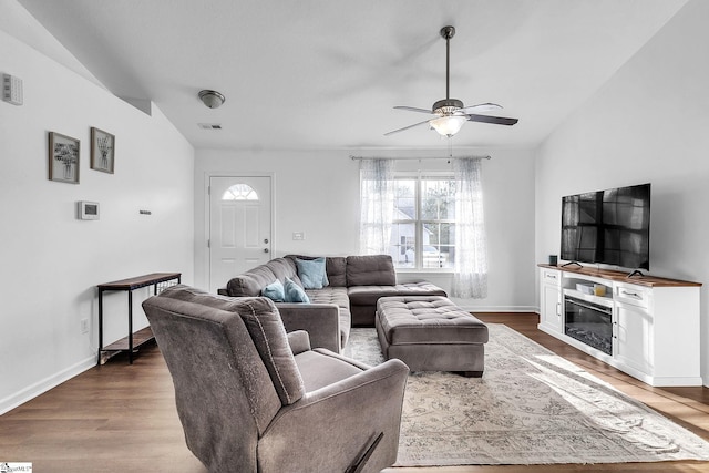 living room featuring baseboards, visible vents, lofted ceiling, ceiling fan, and wood finished floors