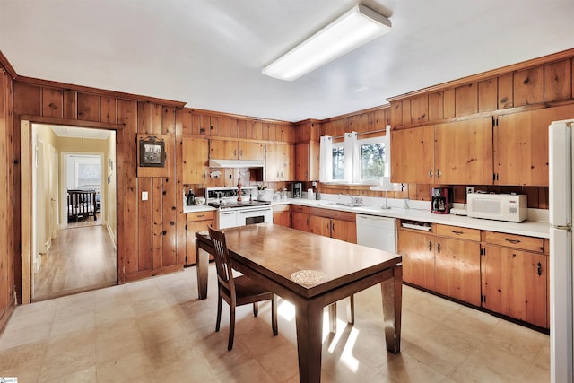 kitchen with light countertops, white appliances, and wood walls