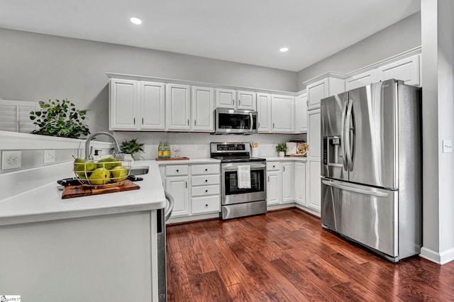 kitchen with light countertops, appliances with stainless steel finishes, dark wood-type flooring, and white cabinets