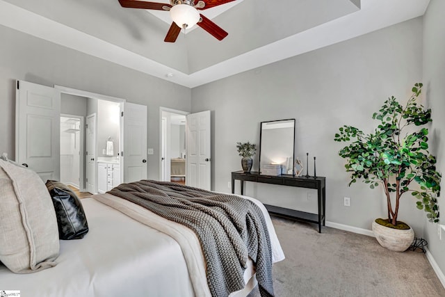 bedroom featuring light carpet, baseboards, a ceiling fan, connected bathroom, and a tray ceiling