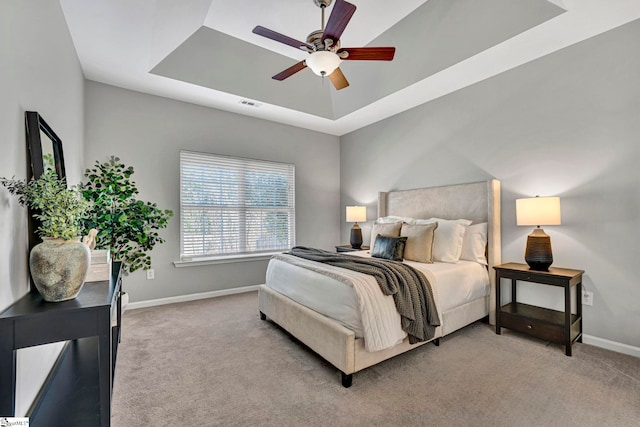 bedroom with baseboards, a tray ceiling, visible vents, and light colored carpet