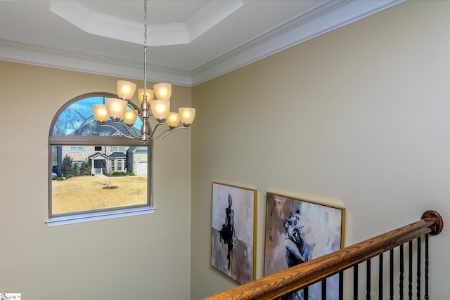 interior space featuring a chandelier, a raised ceiling, and crown molding