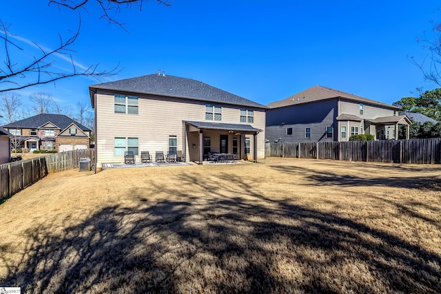 back of house with a fenced backyard, a lawn, and a patio