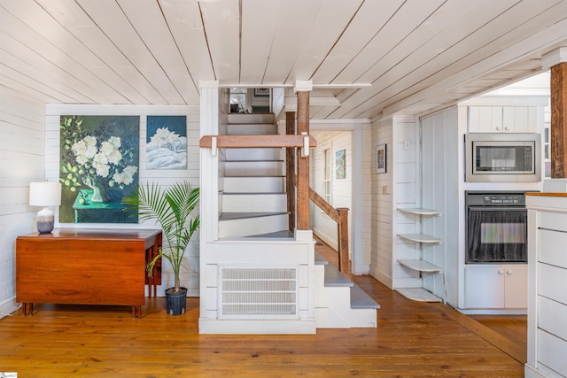 stairs with wood-type flooring, wood ceiling, and wooden walls