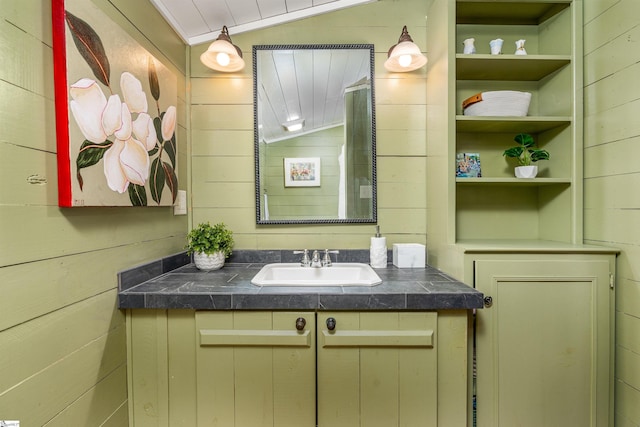 bathroom featuring vaulted ceiling, wood walls, vanity, and built in features