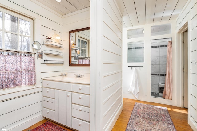 bathroom with wooden walls, wooden ceiling, vanity, and wood finished floors