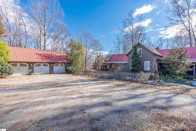 view of side of home with a garage, metal roof, a chimney, and fence