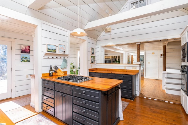 kitchen with wooden walls, hardwood / wood-style flooring, wood counters, appliances with stainless steel finishes, and a peninsula