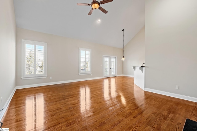 unfurnished living room featuring high vaulted ceiling, french doors, plenty of natural light, and wood finished floors