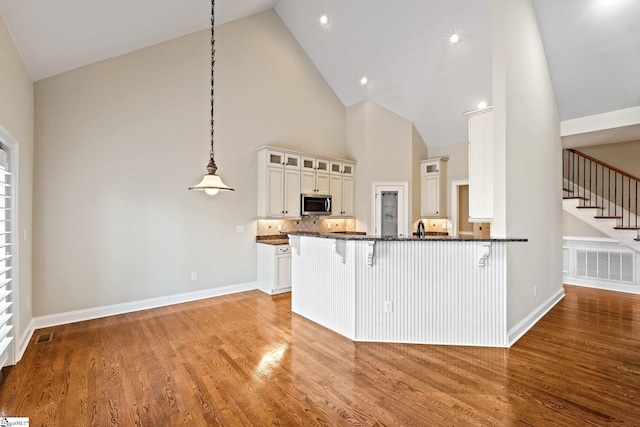 kitchen with light wood-style floors, visible vents, stainless steel microwave, and a breakfast bar