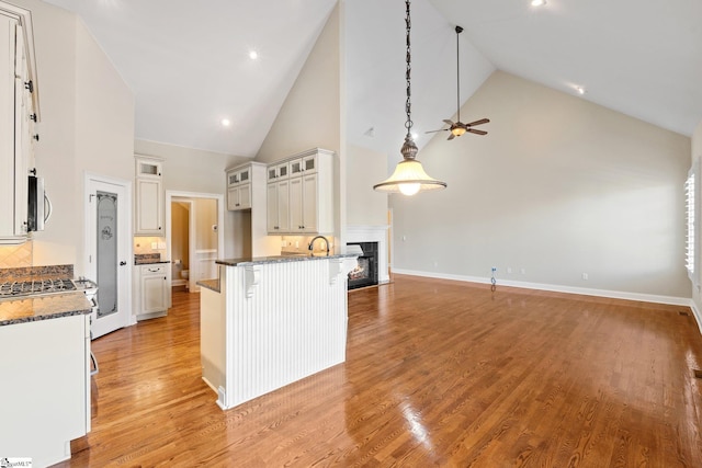 kitchen featuring dark stone counters, stainless steel microwave, light wood finished floors, and a breakfast bar area