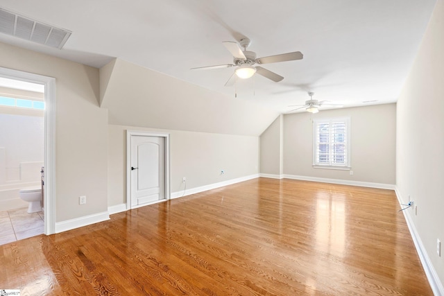 additional living space featuring baseboards, visible vents, vaulted ceiling, and wood finished floors