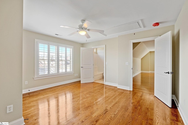 unfurnished bedroom featuring attic access, baseboards, visible vents, a ceiling fan, and wood finished floors