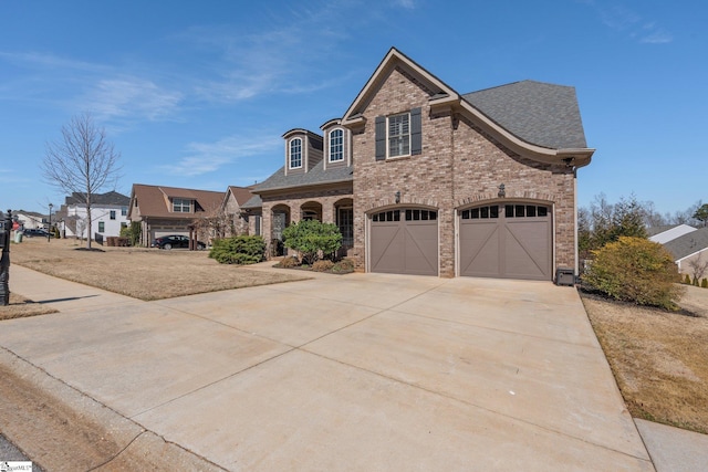 french provincial home featuring concrete driveway, brick siding, and a shingled roof