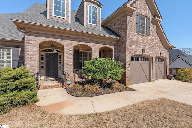 view of front of house featuring a porch, brick siding, driveway, and roof with shingles