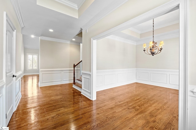 unfurnished room with recessed lighting, wood finished floors, stairway, a tray ceiling, and an inviting chandelier