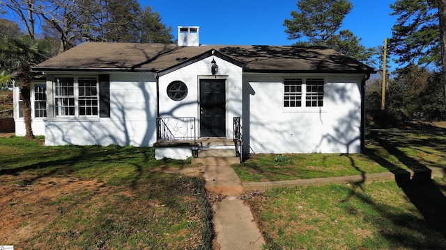 bungalow with a chimney and a front lawn