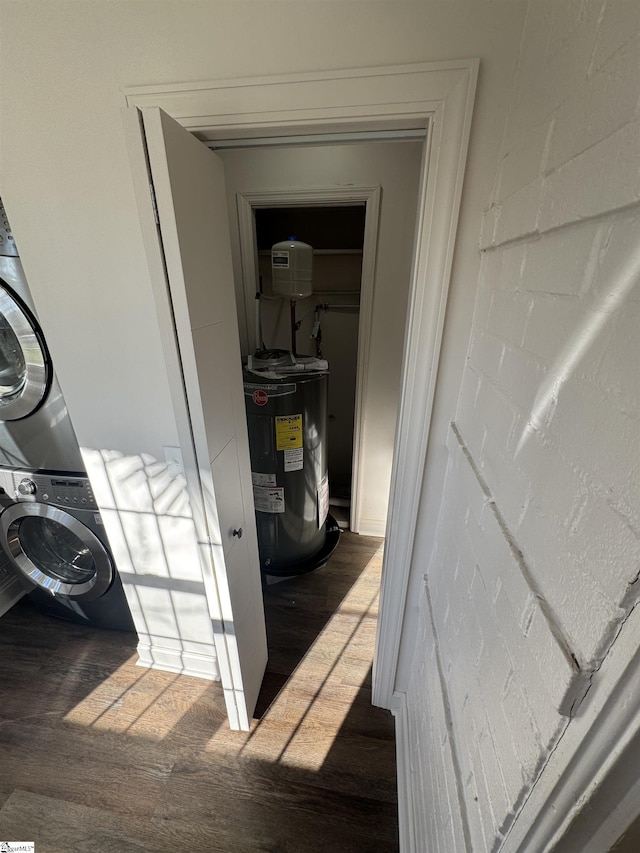 interior details with stacked washer / dryer, electric water heater, and wood finished floors