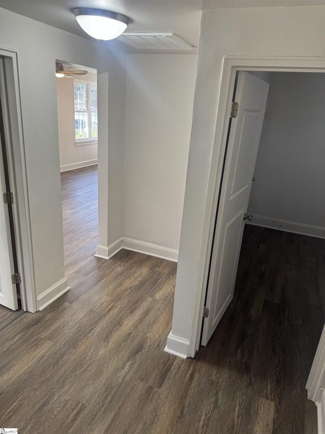 corridor with dark wood-type flooring and baseboards