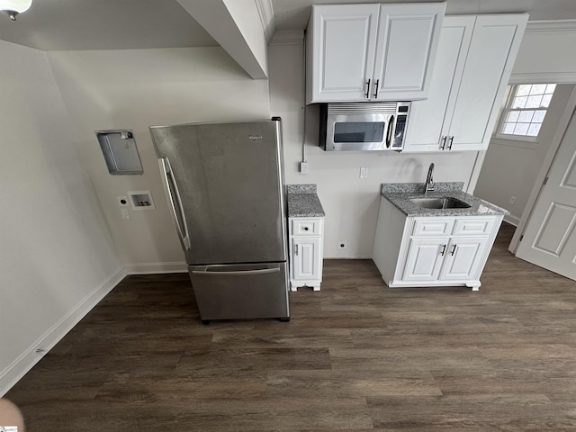 kitchen featuring baseboards, white cabinets, dark wood-type flooring, stainless steel appliances, and a sink
